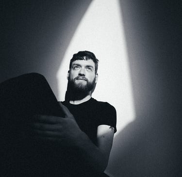 A black and white portrait of a young man sitting on stairs.