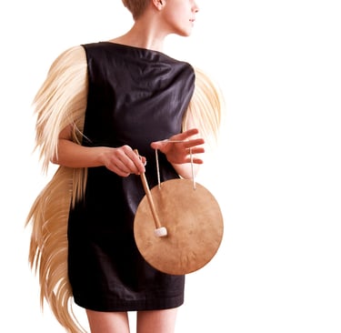 Sandra Kolstad wearing a dress with hair hitting a gong.