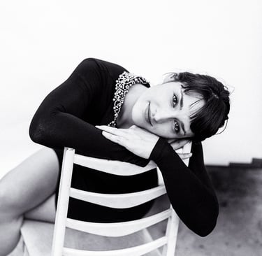 Woman wearing a black dress sitting on a chair.