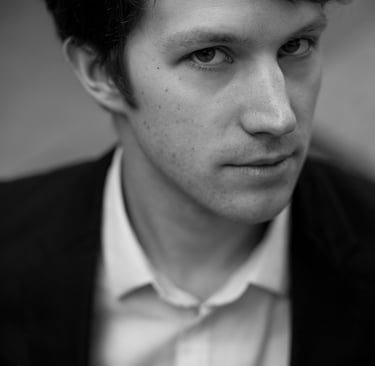 A black and white headshot of a man in a white shirt.