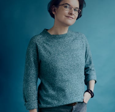 Woman standing in a studio with a blue background.
