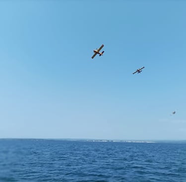 Canadair planes soar from the waters ahead of us.