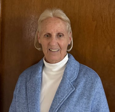A woman with a white turtleneck and blue overcoat