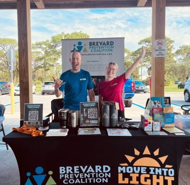 two people standing at information booth hands up and smiling