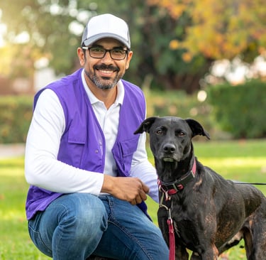 a poof pet waste removal technician wearing the uniform- purple vest and hat, with a dog