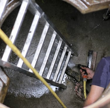 a man in a blue shirt is cleaning a cistern
