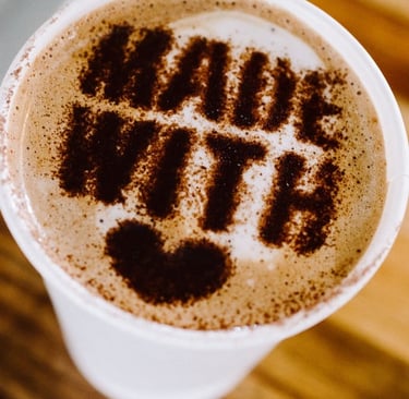Latte art heart with “made with love” message on a coffee cup