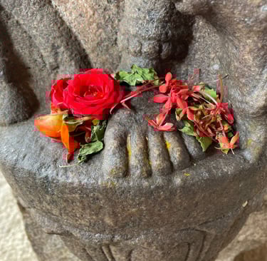 The feet of a statue covered in flowers