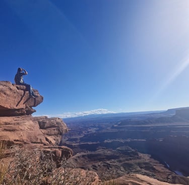 a woman sitting on a rock formation on a sunny day