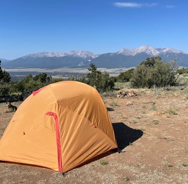 a tent pitched up in a field with mountains in the background