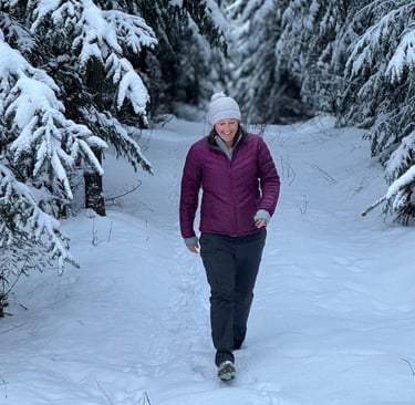 a woman walking through the snow in a forest