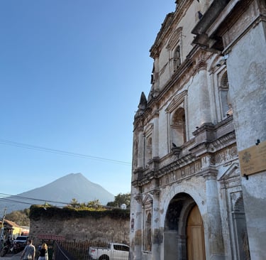 Historic colonial church facade in Antigua Guatemala with a volcano in the background.