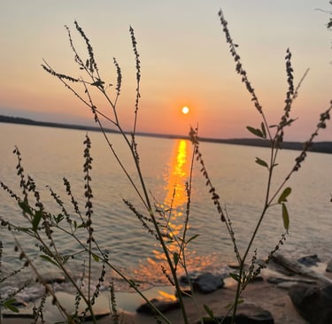 a sunset over a lake with a sun setting
