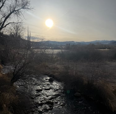a river with a sun setting on the horizon