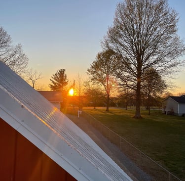 a sunset over a barn roof with a barn roof