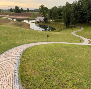 a brick path leading to a pond and a small pond