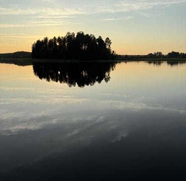 a lake with a few trees and a sky