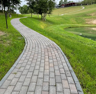 a brick paved path with a path leading to a grassy area