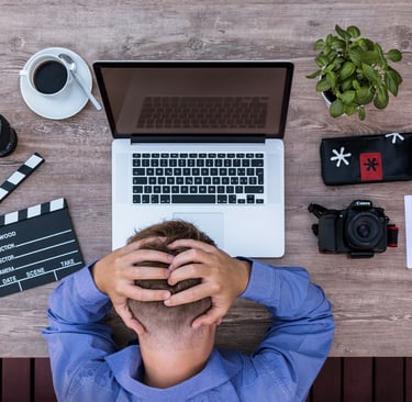 a man sitting at a desk with a laptop and a camera