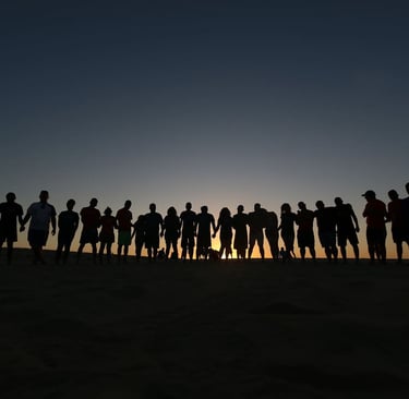 a group of people holding hands in front of a sunset