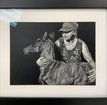 Detailed scratchboard art of a woman hugging a newborn foal in a black frame.