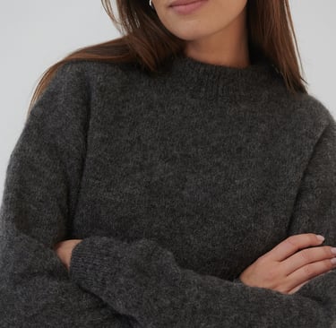 a woman in a gray sweater and a white shirt