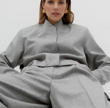 a woman in a grey suit and earrings