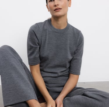 a woman sitting on the floor in a grey sweater