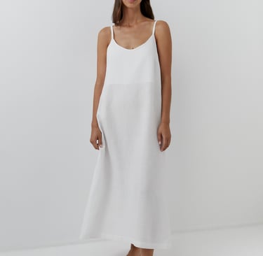 a woman in a white dress standing in front of a white wall