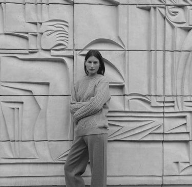 a woman standing in front of a wall with a large wall of art deco