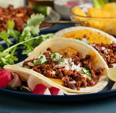 "Tacos Al Pastor served with fresh cilantro, onions, pineapple, and lime, ready to enjoy."