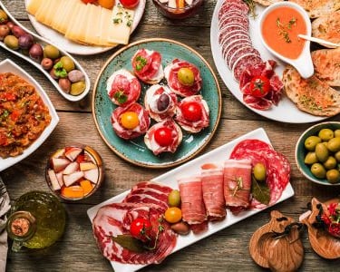 Traditional Spanish dishes including paella, tapas, and churros displayed on a rustic wooden table.