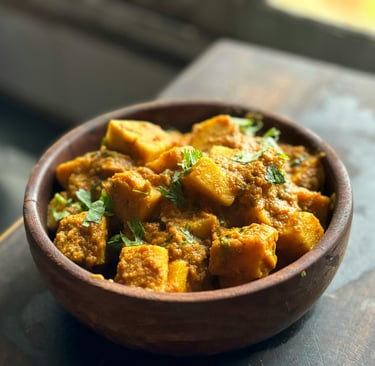 Chicken Tikka Masala served in a traditional copper bowl with rice and naan bread on the side.