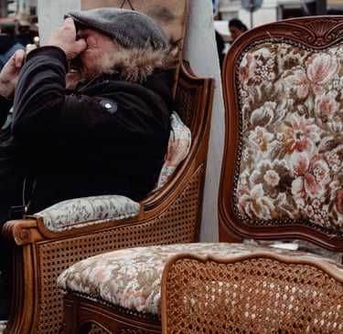 a man sitting on a chair with a hat on