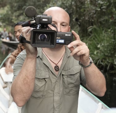 Filmmaker Kevin Augello filming with a Sony camera on a river in the jungle