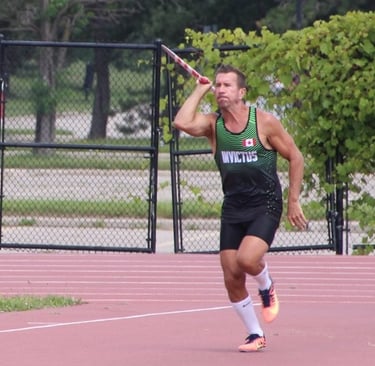 Male athlete mid-javelin throw in competition wearing Canada uniform at ThrowersClub track and field