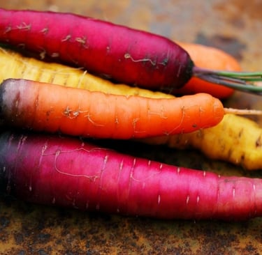a bunch of purple, yellow and orange carrots are sitting on a plate