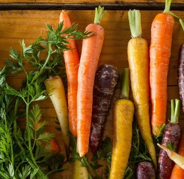 a bunch of colorful carrots are on a wooden table