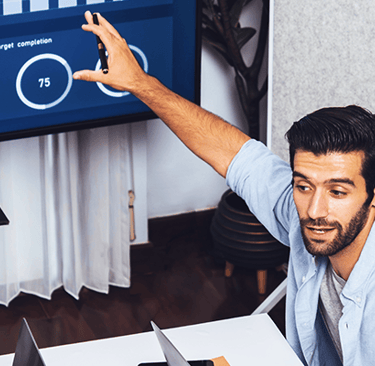 Professional businessman presenting data analytics and KPIs on a digital dashboard screen to his team.