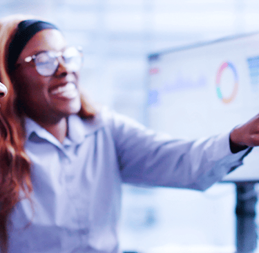 Two business professional women analyzing data charts and analytics on computer monitors.