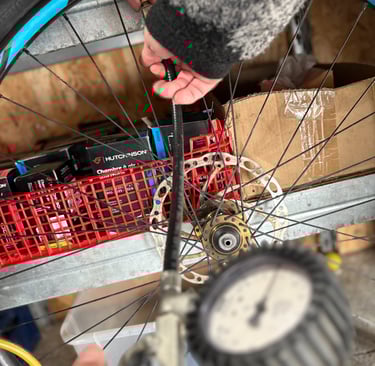 A person inflating a bicycle tire using an air compressor pump with a pressure gauge.