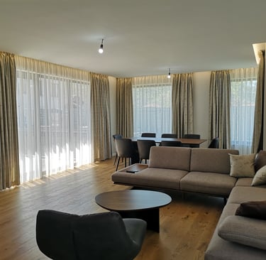 Ein helles Esszimmer mit skandinavischen Möbeln und Fensterfront mit schönen Vorhängen