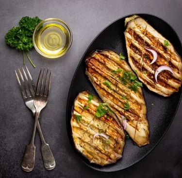 Aubergines grillées sur assiette noire avec bol d'huile d'olive