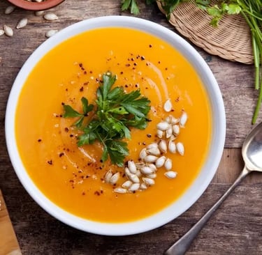 Une assiette de soupe au potiron, posé sur une vieille table en bois.
