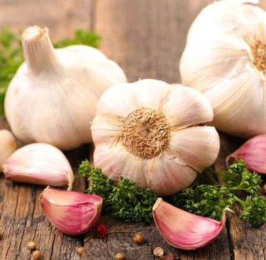 L'ail. Du bulbe à votre assiette. De la terre à votre cuisine.3 gousses d'ails sur une table en bois