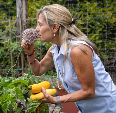 a woman in a blue shirt is holding fresh pick vegetables form the garden 