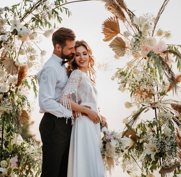 a bride and groom standing in front of a floral arch