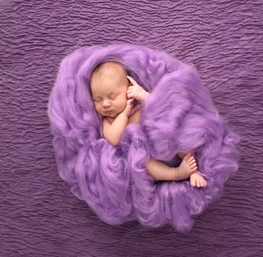 a newborn girl sleeping in a purple blanket