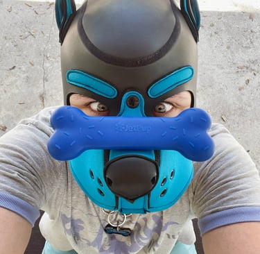 Man in mpup mask with a chew toy balanced on his snout.