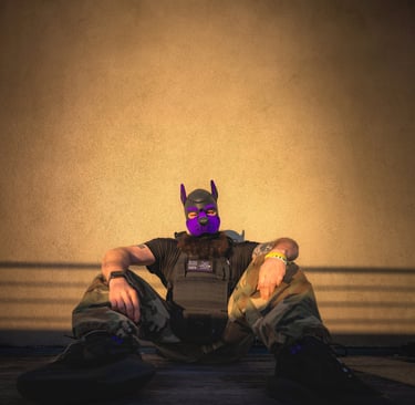 Man in pup mask sitting against a wall.